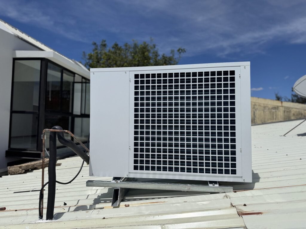 Buitenunit van een airco of warmtepomp op een dak met koelleidingen