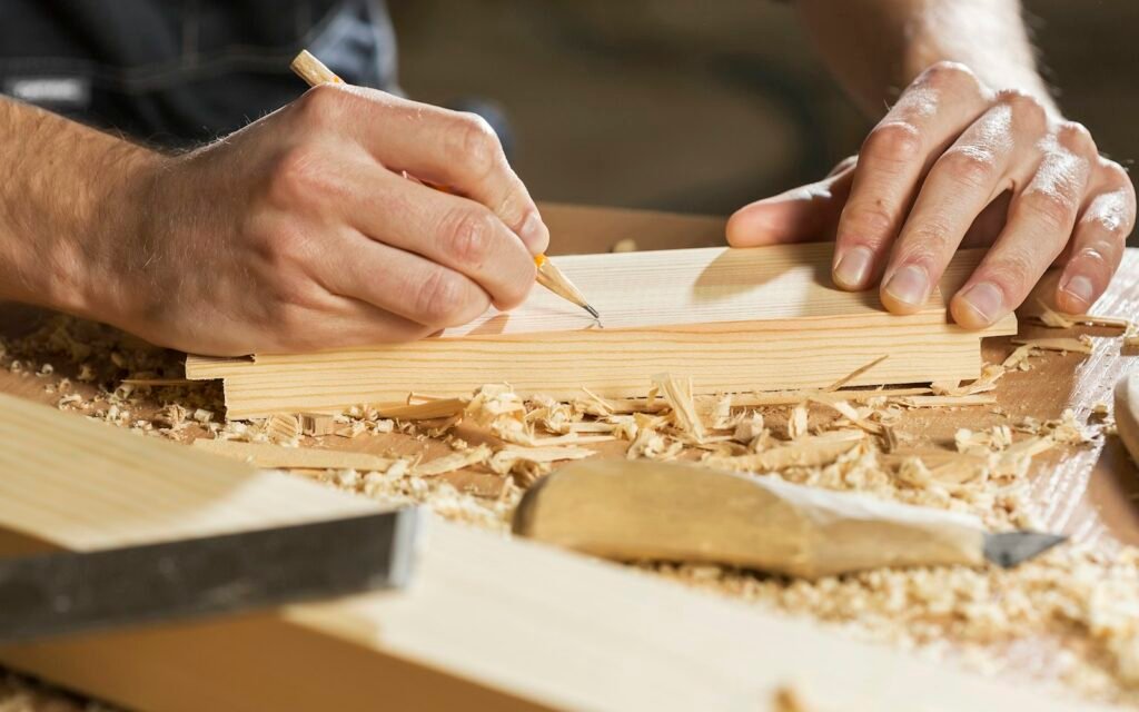 Vakman tekent met potlood een maat af op een houten plank